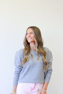 Woman wearing a gray sweater against a white background