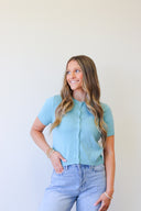 Woman wearing a light blue cardigan and jeans against a white background